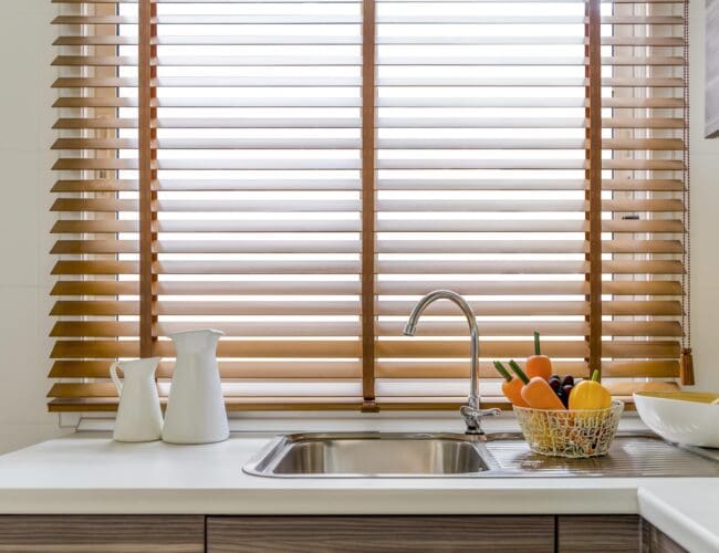 Wooden Venetian blinds in a bright kitchen window.