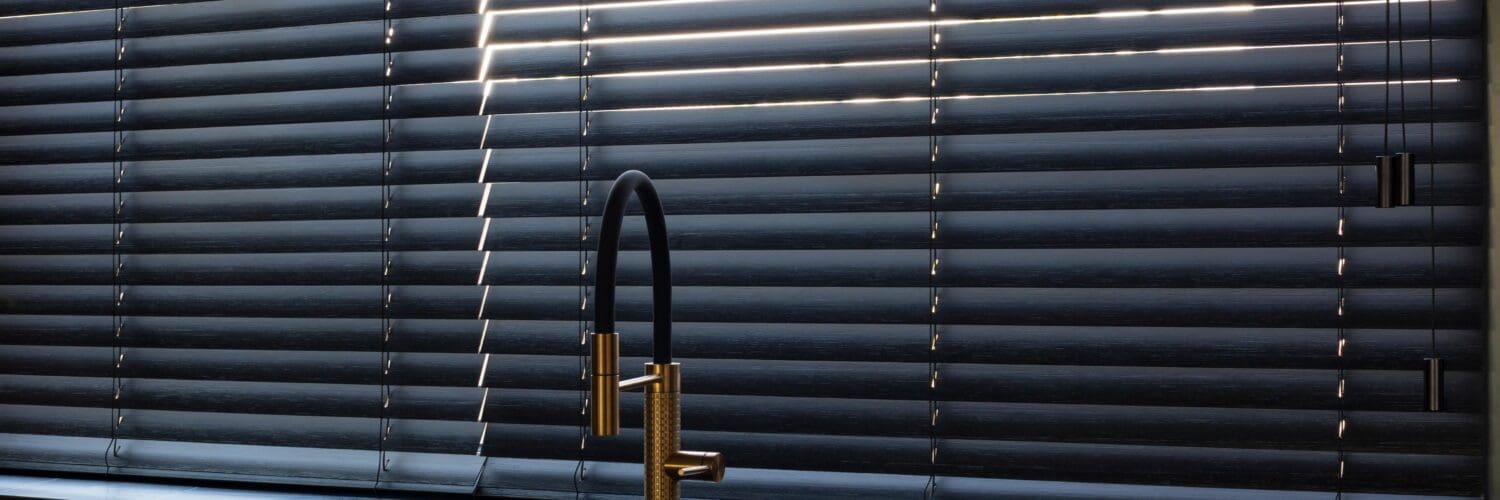 Modern black Venetian blinds in a contemporary kitchen window.